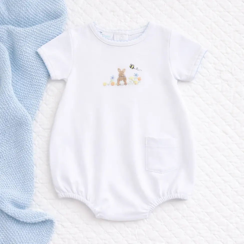 White baby romper with embroidered design on a textured white surface