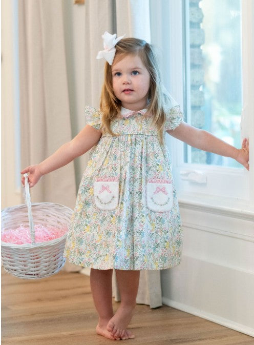 Young girl in a floral dress holding a basket indoors